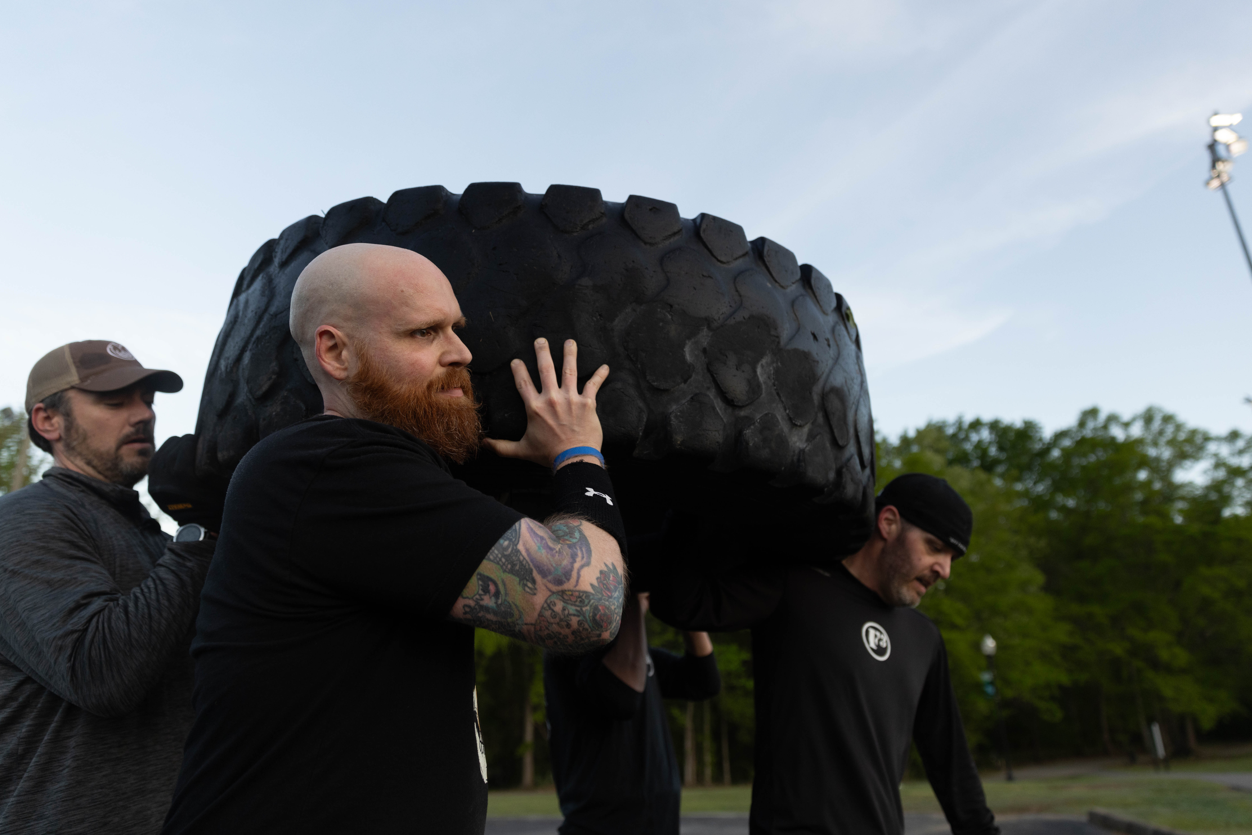 A member shouldering a tire at a workout